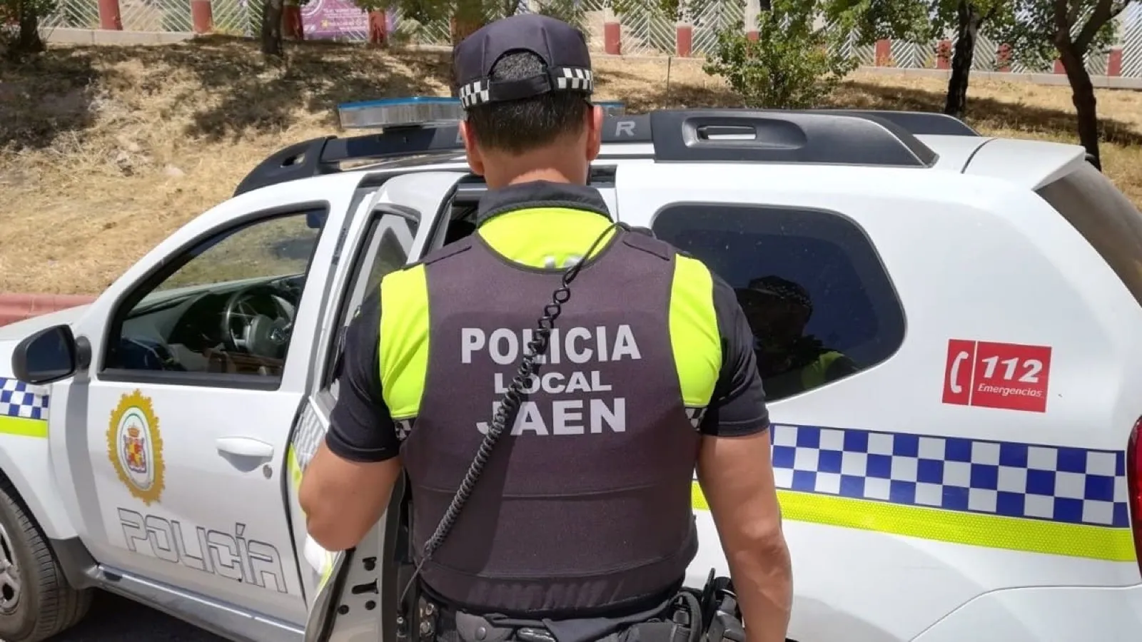 Agente de la Policía Local de Jaén junto al vehículo patrulla